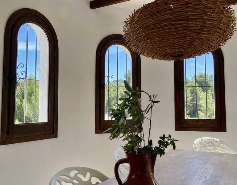 This villa in Benissa has a cozy dining room with many windows overlooking the greenery.